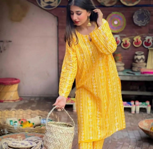 Woman in a yellow traditional outfit holding a basket in a decorative setting.