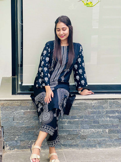 Woman wearing a navy blue traditional outfit with white patterns sitting on steps.