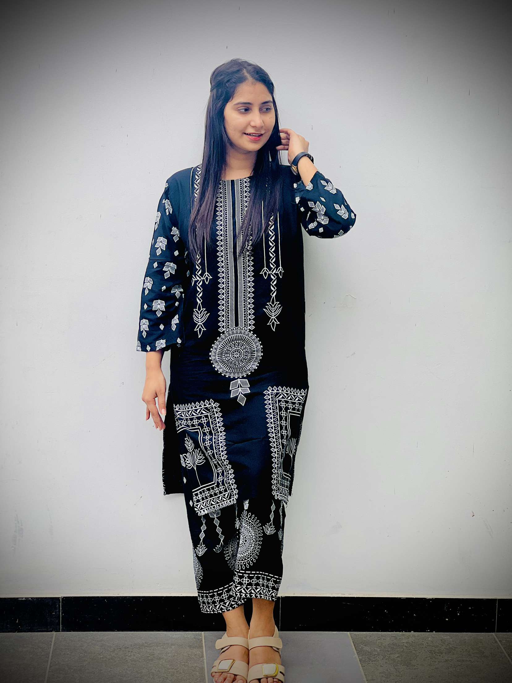 Woman wearing a black embroidered outfit against a plain background