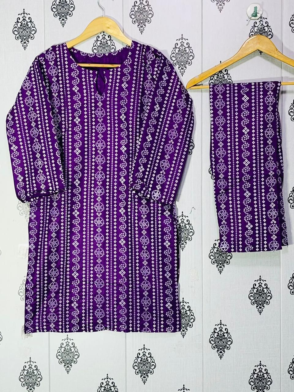 Purple patterned kurta with matching pants on a hanger against a decorative wall.
