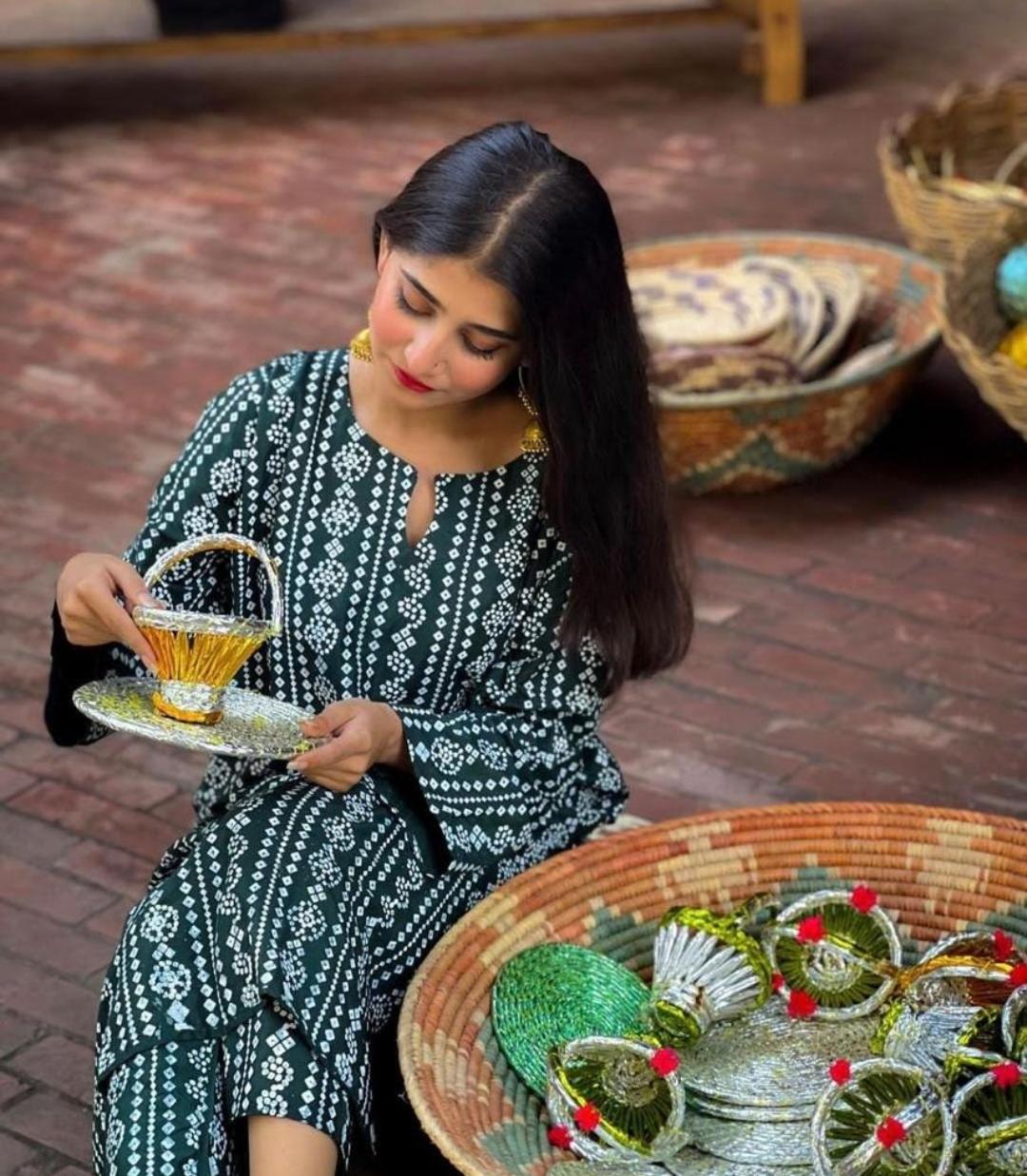 Woman in traditional attire holding a teacup in a rustic setting