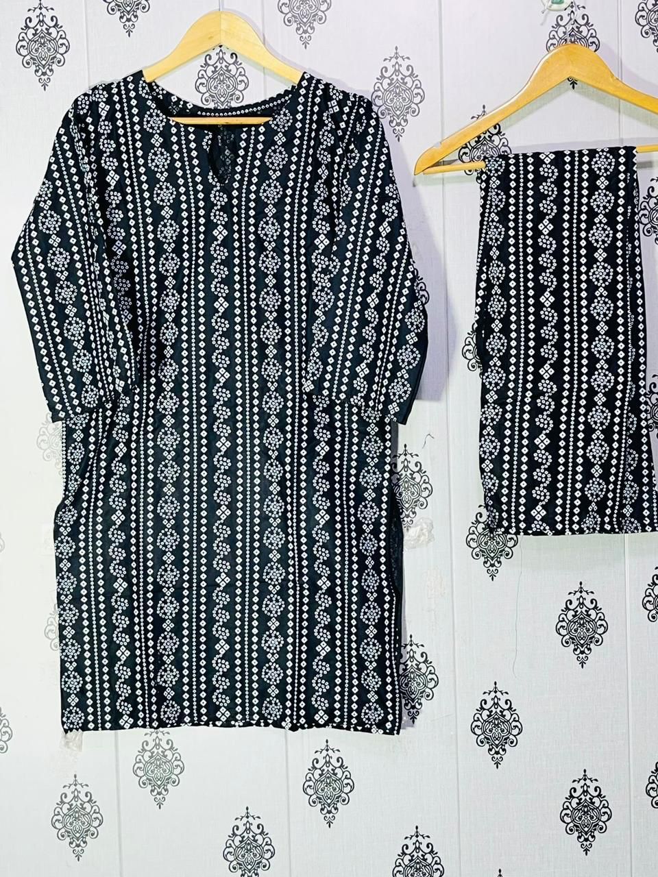 Black and white patterned garment on a hanger against a decorative wall.